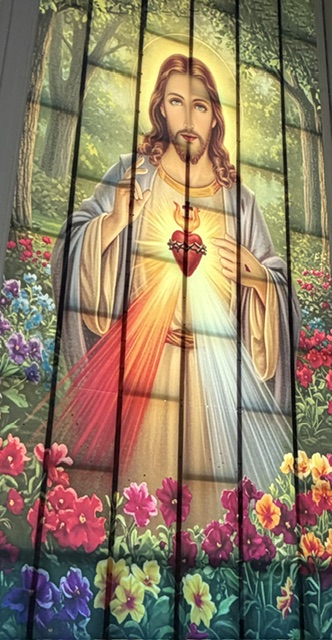 An image of the Sacred Heart of Jesus surrounded by a garden of flowers.